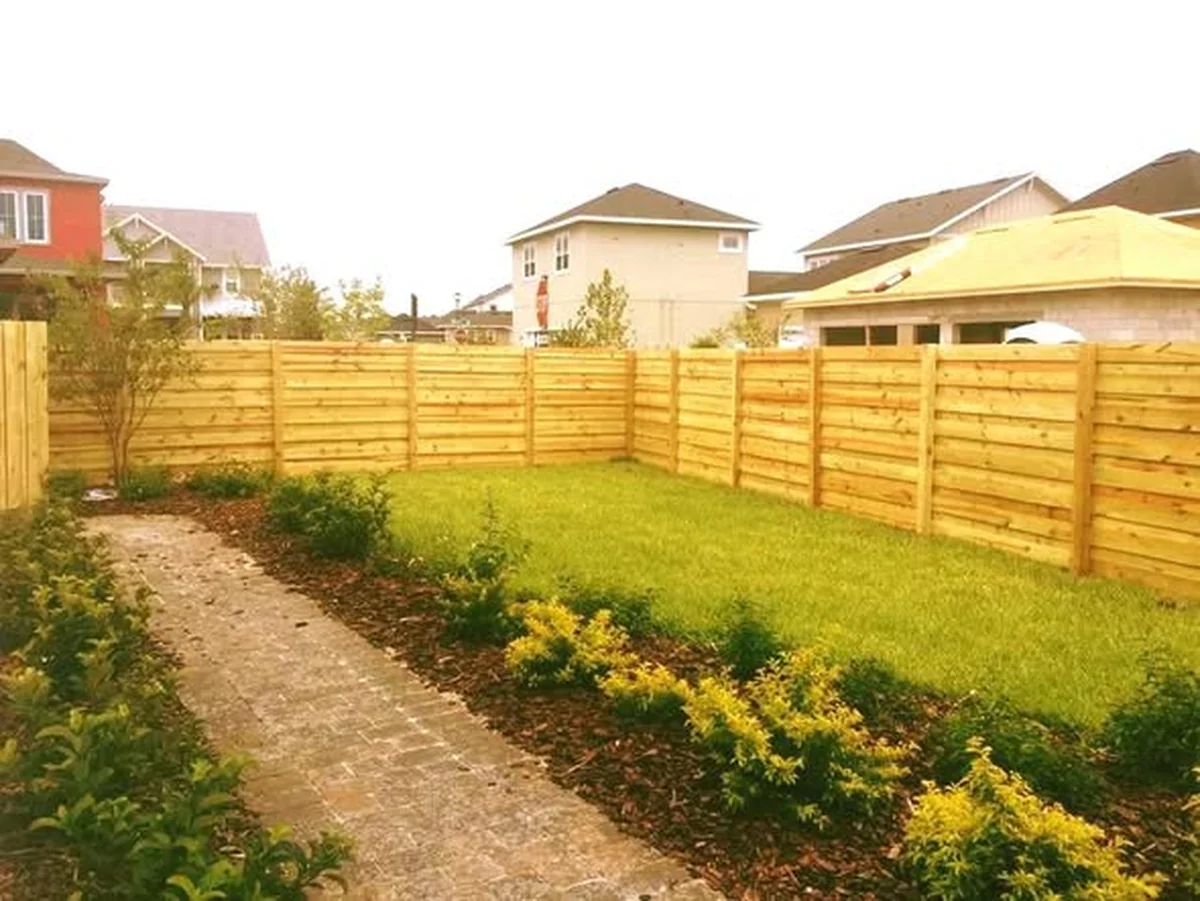 Horizontal slat wood fence enclosing a landscaped side yard
