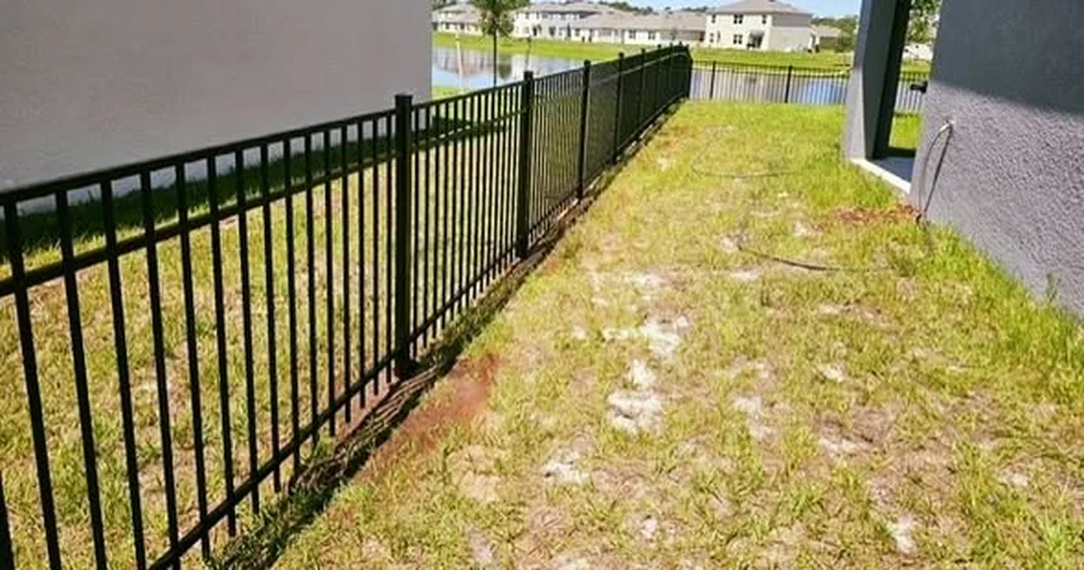 Black aluminum fence running along a St. Cloud property near the lake