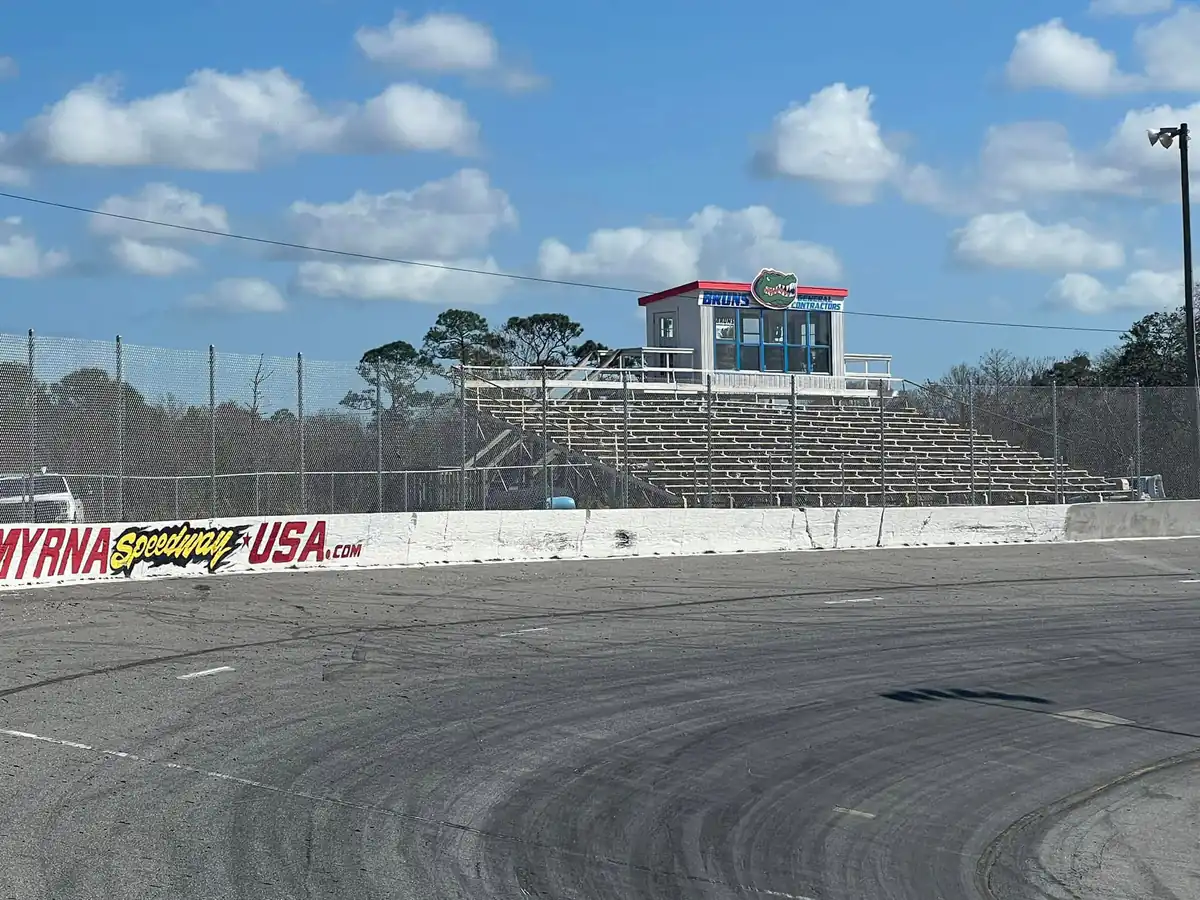 Tall galvanized chain link catch fence installed along a speedway front stretch