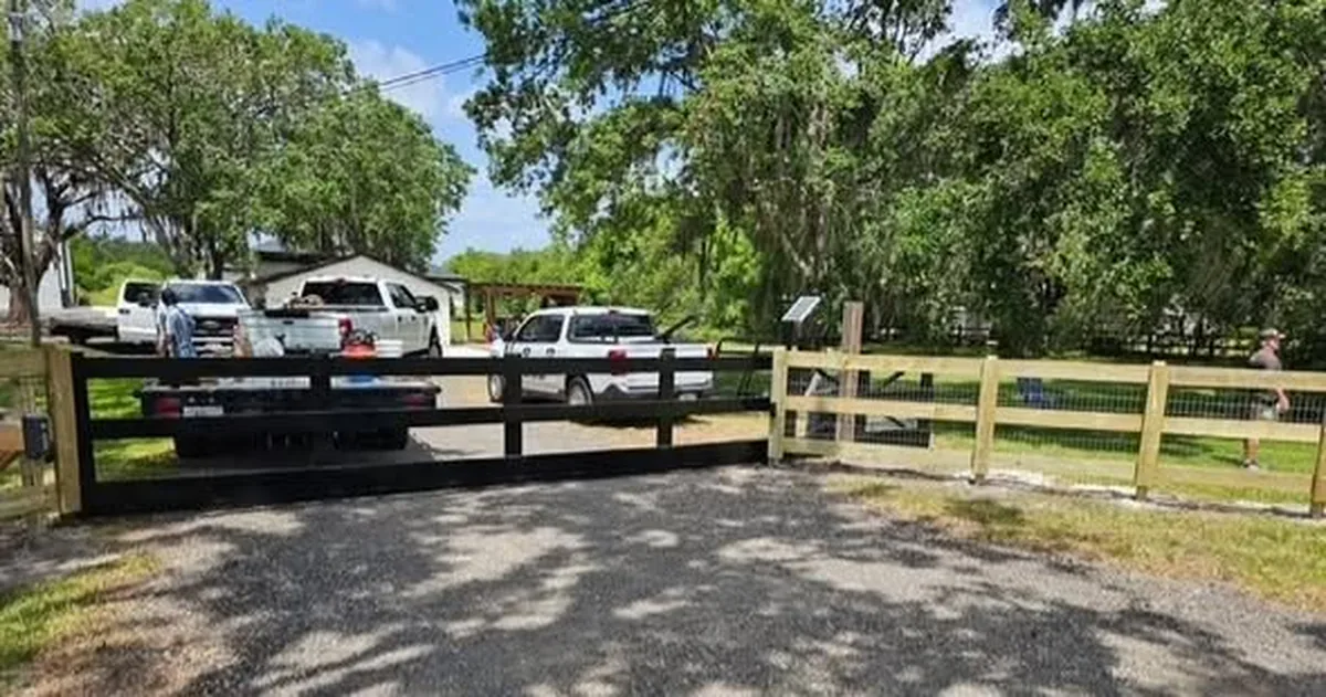 Three rail wood fence with wire backing framing a Winter Park driveway entrance