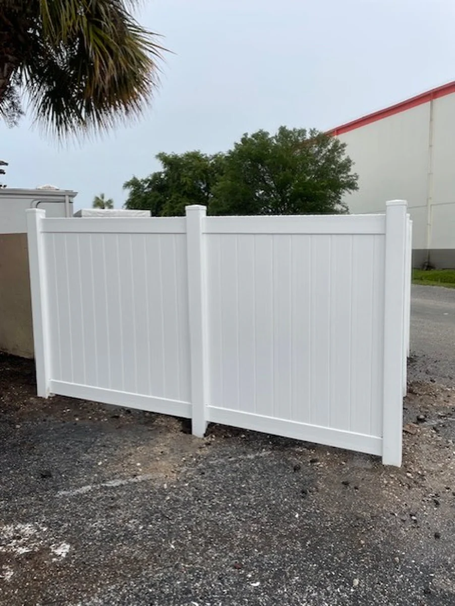 White vinyl privacy panels forming the side wall of a dumpster enclosure in Orlando