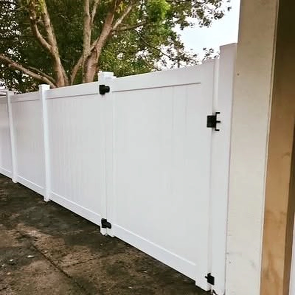 White vinyl privacy fence and gate among trees in Winter Garden