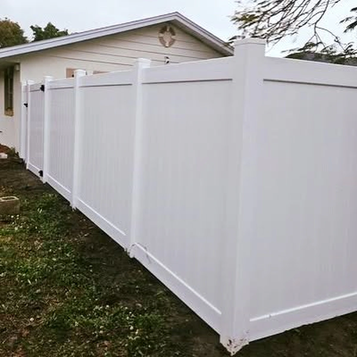 White vinyl fence turning a corner among trees in Winter Garden