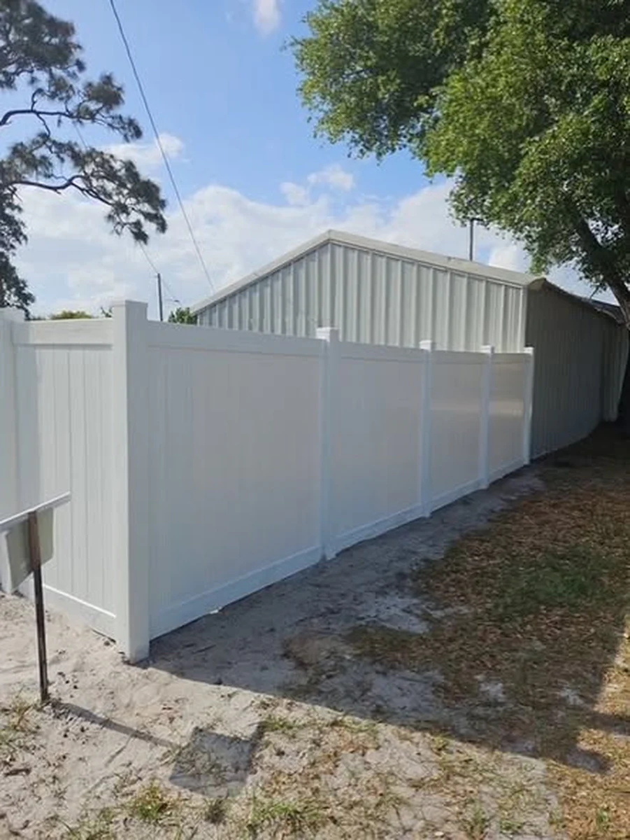 White vinyl privacy fence beside a metal commercial building in Orlando