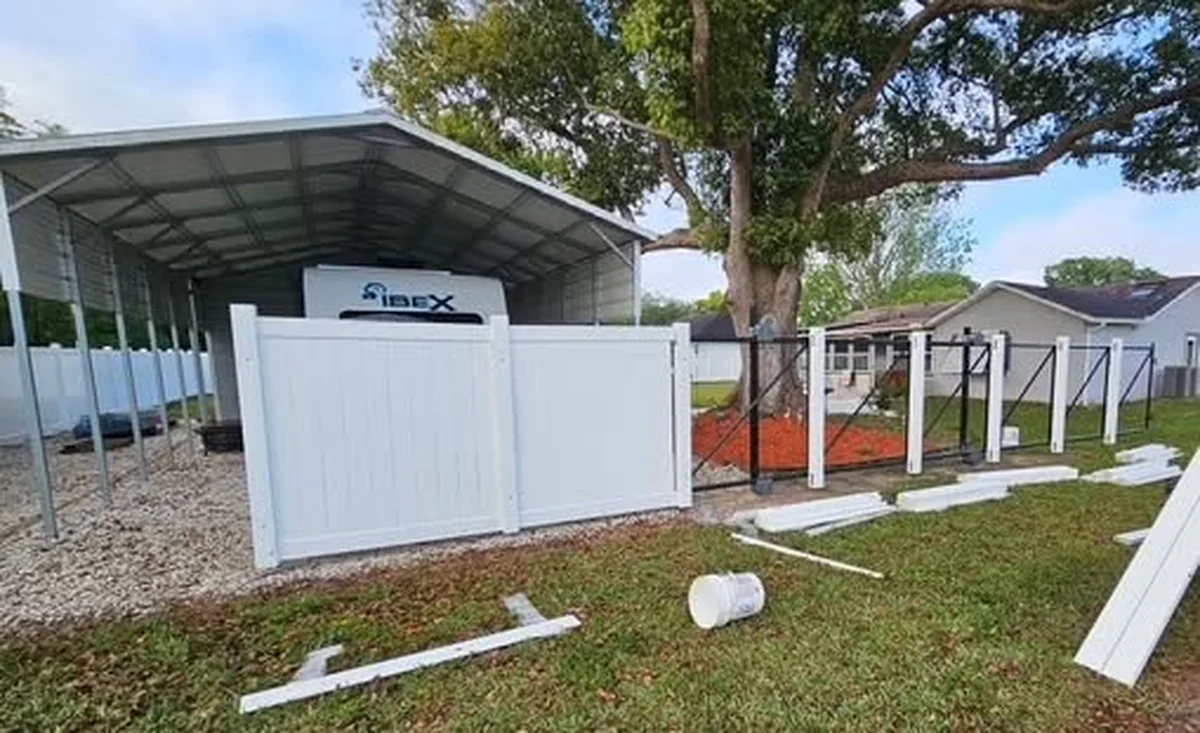 Metal reinforced vinyl gate hung at a St. Cloud car port during installation, with the run still in progress