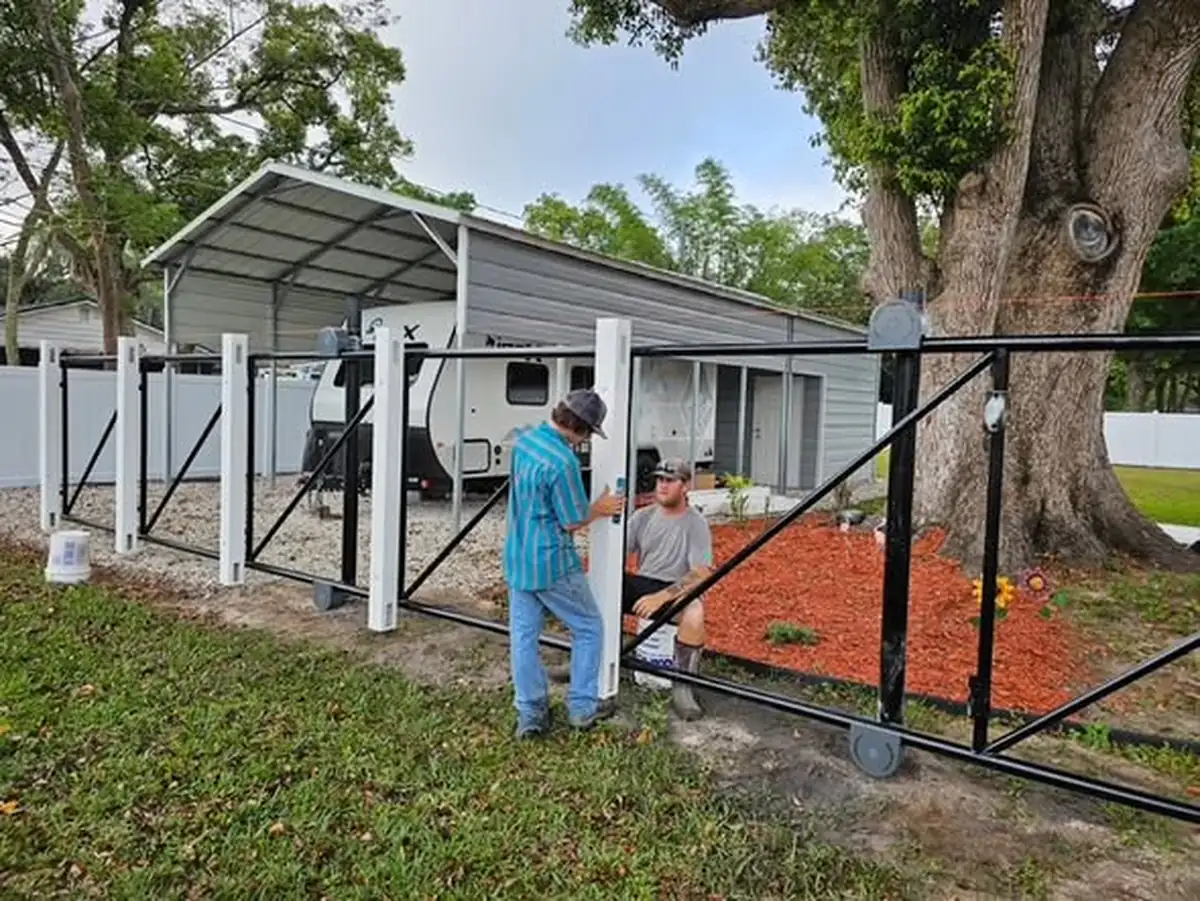 Vinyl fence posts set in concrete around a St. Cloud car port during installation