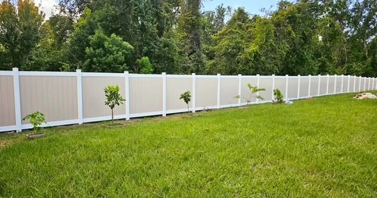 White vinyl privacy fence across a Winter Garden back yard with small trees
